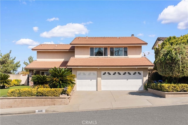 view of front facade with stucco siding, concrete driveway, an attached garage, and a tiled roof