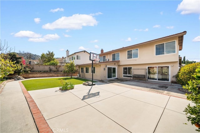 back of house with a patio, a lawn, fence, and stucco siding