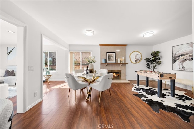 dining room featuring baseboards, a large fireplace, and wood finished floors