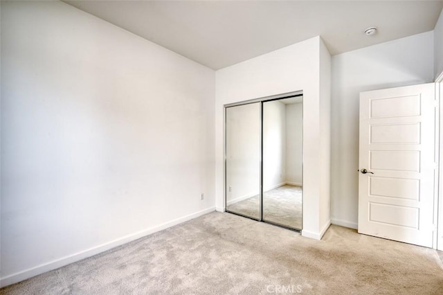 unfurnished bedroom with carpet flooring, baseboards, and a closet