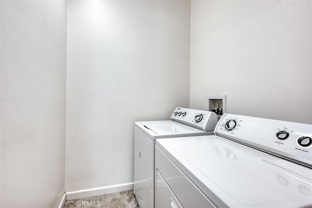 clothes washing area featuring baseboards, separate washer and dryer, and laundry area