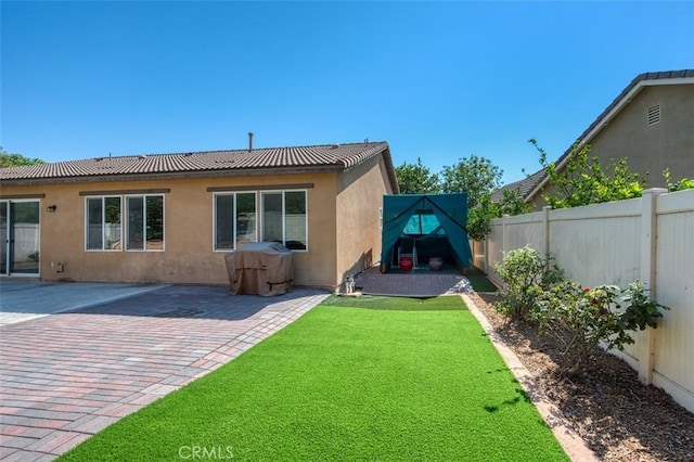 back of house featuring a patio, a yard, a fenced backyard, and stucco siding