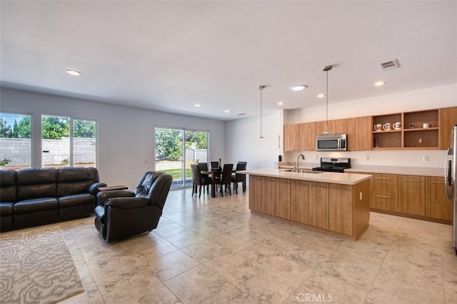 kitchen featuring modern cabinets, a sink, open floor plan, appliances with stainless steel finishes, and light countertops