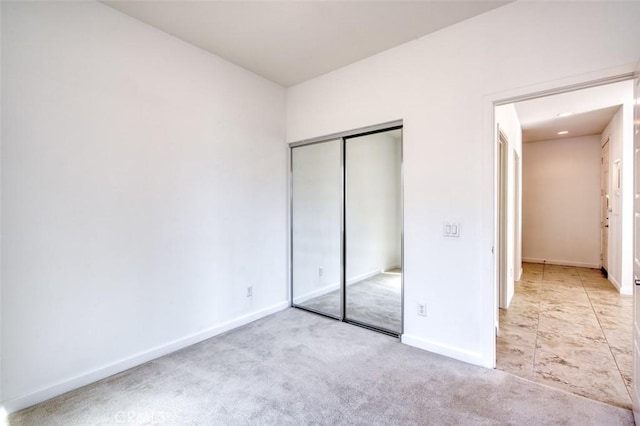 unfurnished bedroom with a closet, baseboards, and carpet