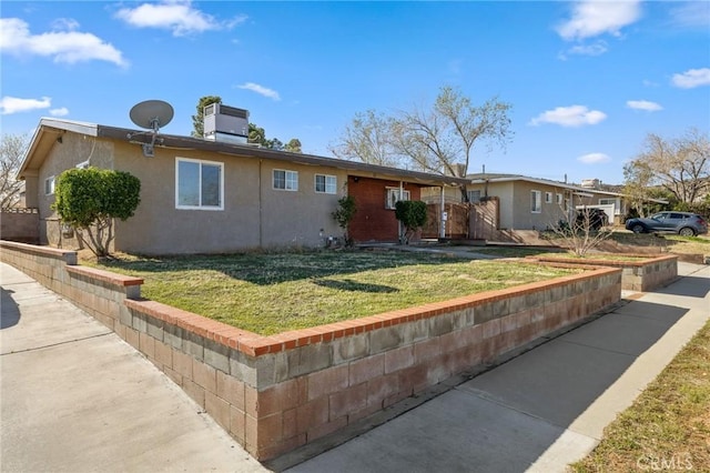 view of front of property with stucco siding, cooling unit, and a front lawn