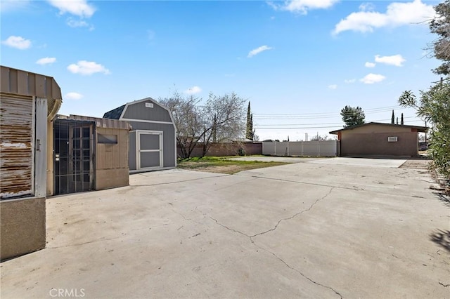 view of patio featuring an outbuilding, a storage shed, and fence