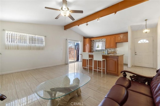 living room with baseboards, a ceiling fan, and vaulted ceiling with beams