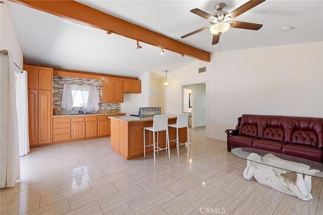 kitchen featuring visible vents, vaulted ceiling with beams, a kitchen bar, open floor plan, and a center island