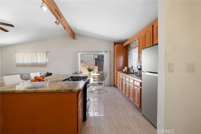 kitchen with lofted ceiling with beams, a sink, ceiling fan, stainless steel appliances, and open floor plan