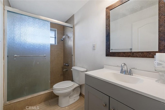 bathroom featuring toilet, a stall shower, and vanity