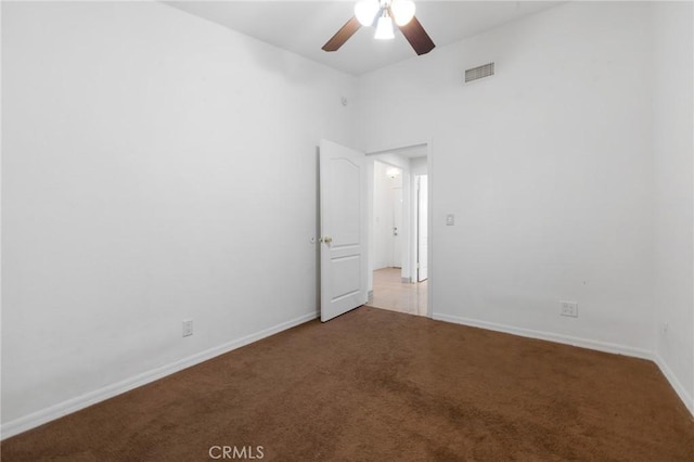 carpeted spare room featuring visible vents, baseboards, and ceiling fan