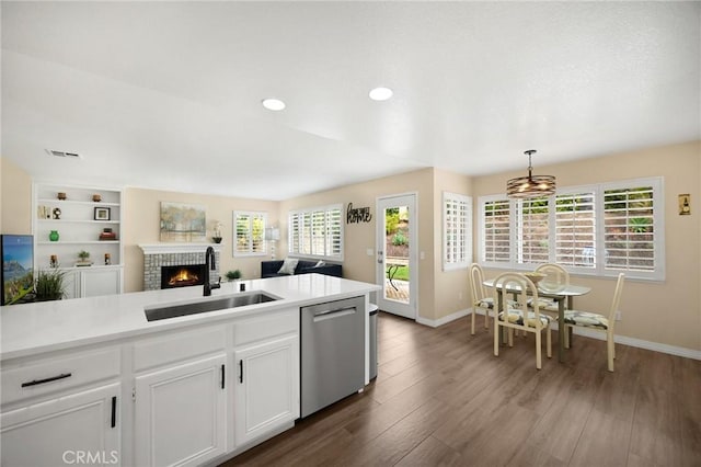 kitchen with visible vents, a sink, open floor plan, wood finished floors, and stainless steel dishwasher