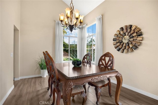 dining space with wood finished floors, baseboards, and a chandelier