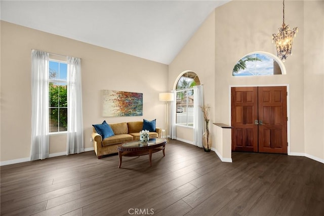 foyer entrance featuring a notable chandelier, baseboards, dark wood-style flooring, and high vaulted ceiling