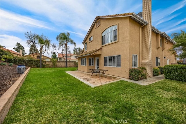 back of house featuring fence, a yard, stucco siding, a chimney, and a patio area