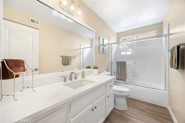 bathroom with visible vents, toilet, a textured ceiling, wood finished floors, and vanity