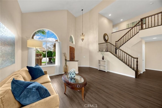 living room featuring baseboards, a chandelier, stairway, a high ceiling, and wood finished floors