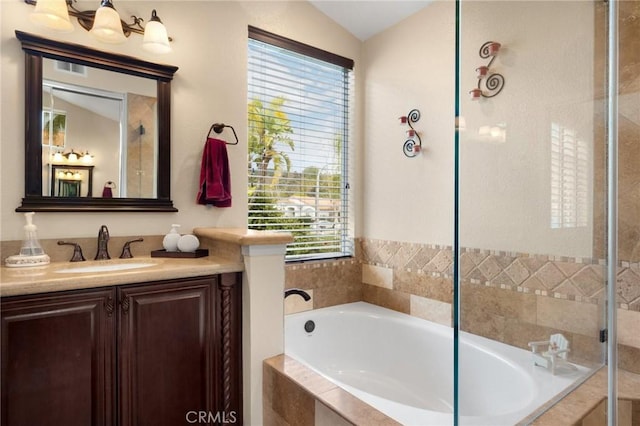 full bath featuring plenty of natural light, vanity, a garden tub, and vaulted ceiling