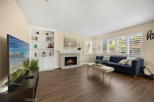 living room featuring dark wood-style floors, built in features, a fireplace, and baseboards