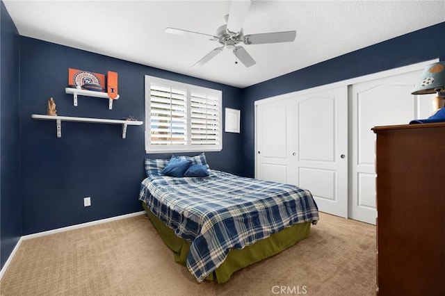 carpeted bedroom with a closet, baseboards, and ceiling fan