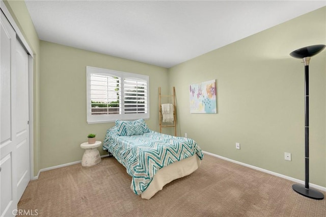 carpeted bedroom featuring baseboards and a closet