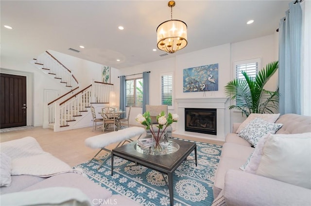 living room featuring visible vents, a chandelier, stairs, recessed lighting, and a glass covered fireplace