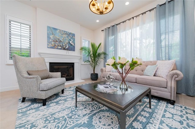 living area with a chandelier, a glass covered fireplace, recessed lighting, and baseboards