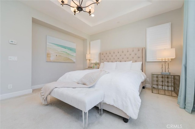 bedroom with a tray ceiling, carpet floors, a notable chandelier, and baseboards