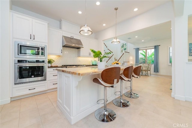 kitchen with decorative backsplash, appliances with stainless steel finishes, white cabinetry, and under cabinet range hood