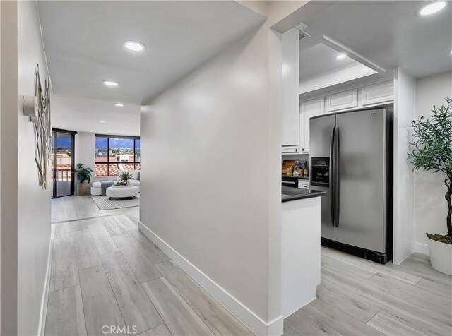 hall featuring floor to ceiling windows, recessed lighting, baseboards, and light wood-type flooring