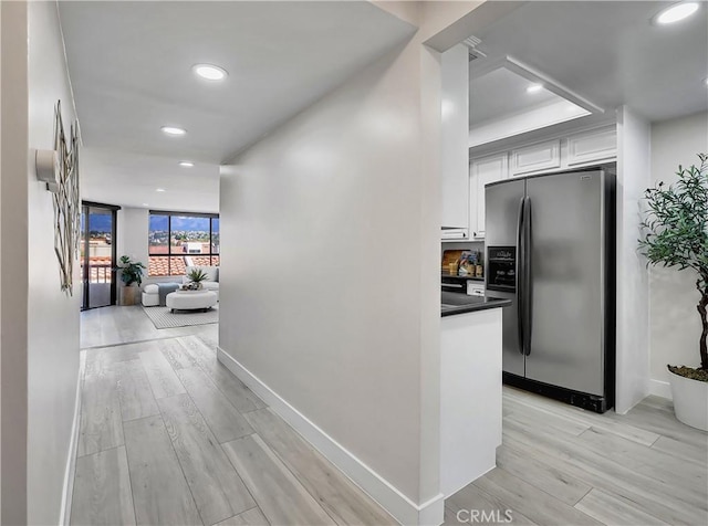 hall featuring recessed lighting, baseboards, and light wood-style flooring