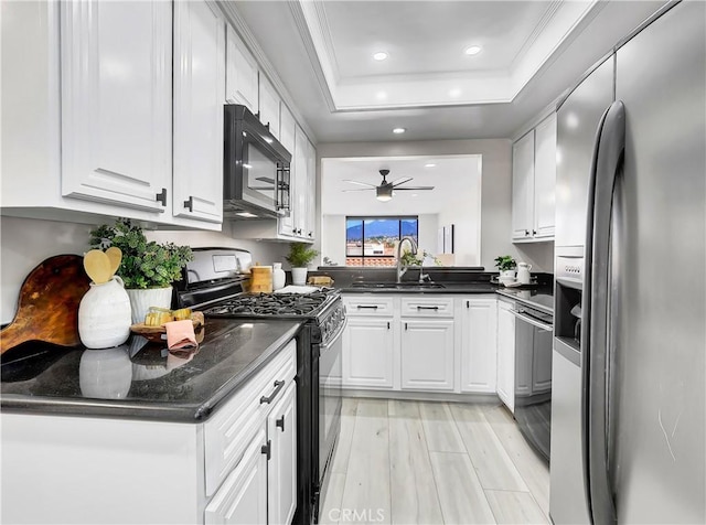 kitchen featuring a ceiling fan, a sink, a raised ceiling, black appliances, and white cabinetry
