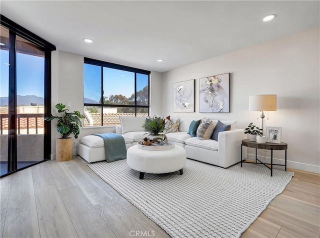 living room with recessed lighting, floor to ceiling windows, baseboards, and wood finished floors