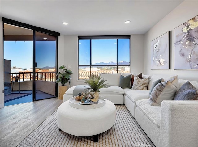 living area with recessed lighting, a wall of windows, a mountain view, and wood finished floors
