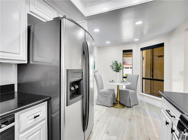 kitchen featuring stainless steel refrigerator with ice dispenser, dark countertops, white cabinetry, and light wood-style flooring