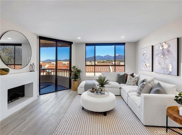 living room with wood finished floors, a fireplace, recessed lighting, a mountain view, and floor to ceiling windows