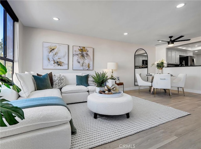 living room with light wood-type flooring, a ceiling fan, baseboards, and recessed lighting