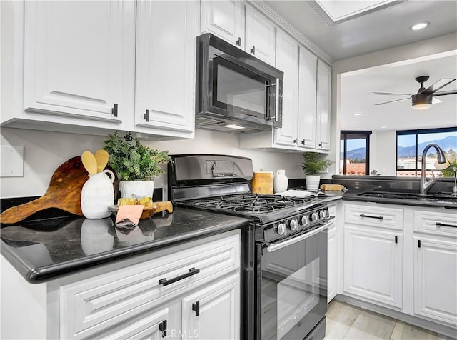 kitchen with a sink, ceiling fan, black appliances, and white cabinetry