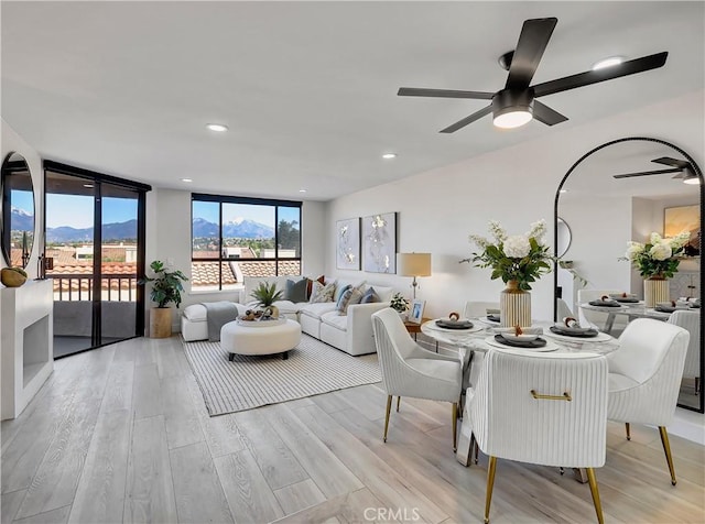 dining room featuring a ceiling fan, a mountain view, expansive windows, and light wood-style flooring