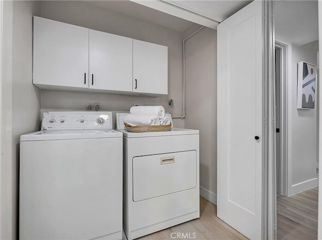 washroom with washing machine and clothes dryer, cabinet space, light wood finished floors, and baseboards