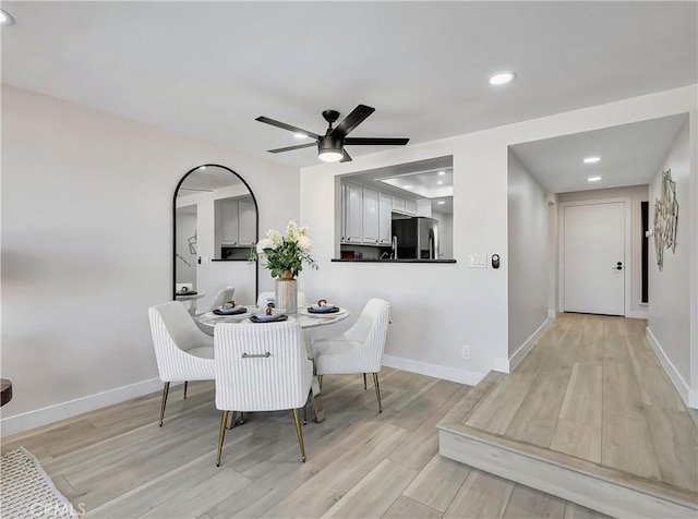 dining room featuring baseboards, ceiling fan, and light wood finished floors