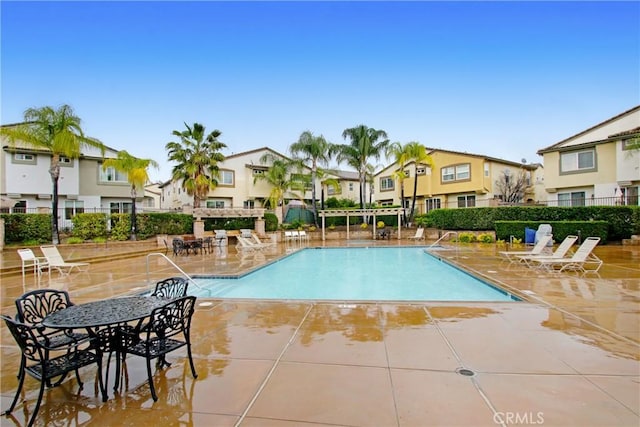 community pool featuring a patio area, fence, and a residential view