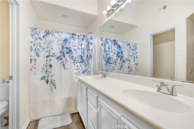 bathroom featuring visible vents, toilet, wood finished floors, and a sink