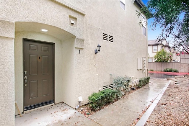 property entrance featuring stucco siding and fence