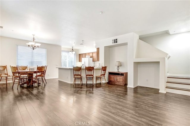 dining area with visible vents, baseboards, dark wood finished floors, stairs, and a notable chandelier