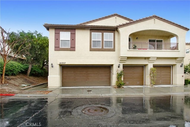 view of front of property with stucco siding, a balcony, an attached garage, and a tiled roof