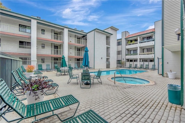 community pool featuring a community hot tub and fence