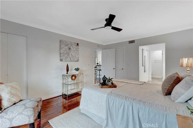 bedroom with wood finished floors, baseboards, visible vents, ceiling fan, and ornamental molding