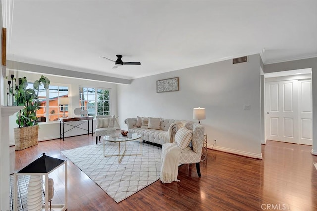 living area with visible vents, ornamental molding, baseboards, and wood finished floors