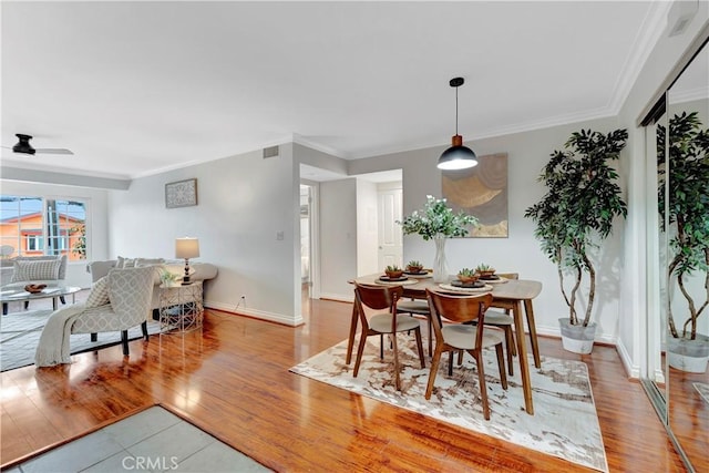 dining space with visible vents, crown molding, ceiling fan, baseboards, and wood finished floors